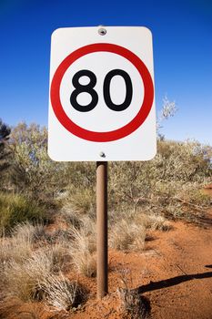 Australian kilometer per hour speed limit sign by rural dirt road.