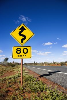 Kilometer per hour speed limit and curve ahead road signs in rural Australia.