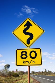 Kilometer per hour speed limit and curve ahead road signs in rural Australia.