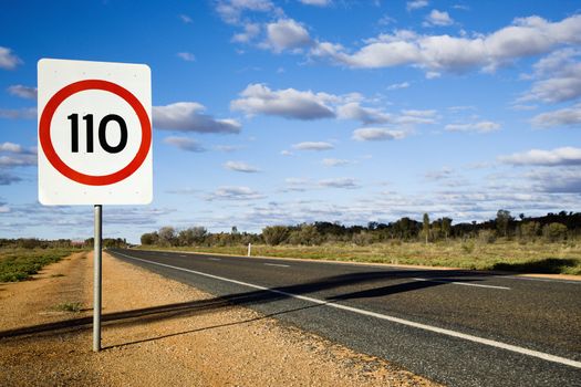 Speed limit kilometer per hour road sign by road in rural Australia.