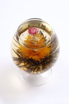 Glass with a blooming flower green tea on white background