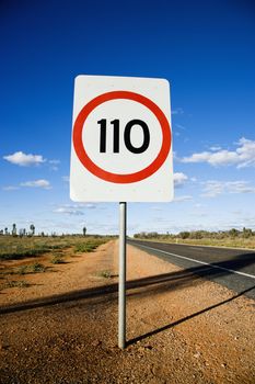 Speed limit kilometer per hour road sign by road in rural Australia.