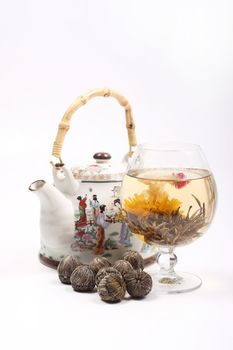 Teapot and Glass with a blooming flower green tea on white background