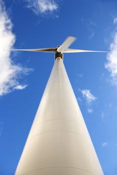 Perspective shot of wind turbine against blue sky.