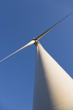 Perspective shot of wind turbine against blue sky.