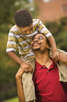 Father carrying his son on his shoulders smiling and looking at eachother.