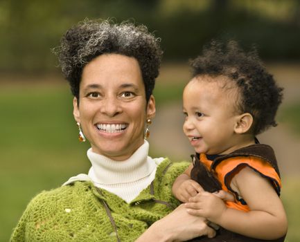 Head and shoulder portrait of woman holding boy and smiling.