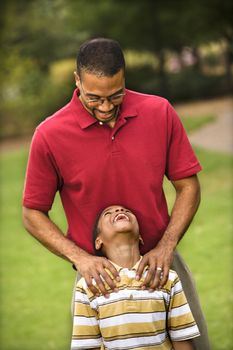 Father standing behind son with hands on his shoulders as boy smiles.