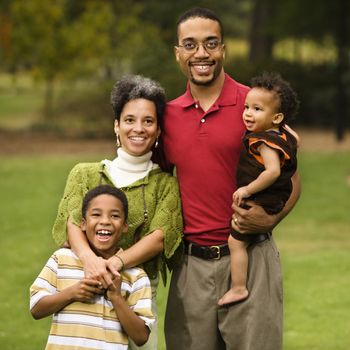 Portrait of happy smiling family of four in park.