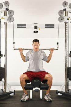 Man at gym lifting weights on weight machine.