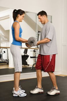 Man and woman lifting weights in gym.