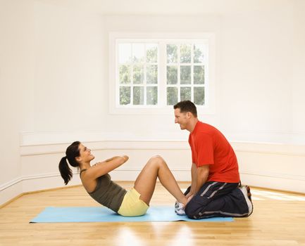 Man holding woman's feet down as she does sit up exercises.