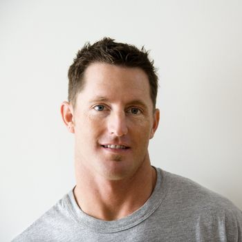 Head and shoulder portrait of man in t-shirt against white wall.