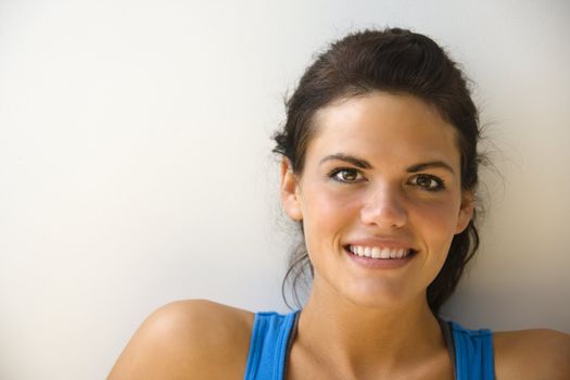 Head and shoulder portrait of woman in fitness attire smiling.