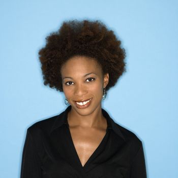 Head and shoulder studio portrait of smiling happy woman on blue background.