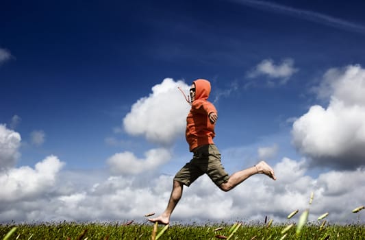 Man running and jumping on a green meadow