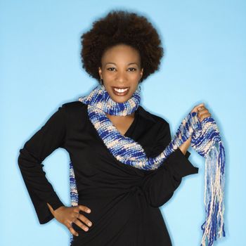 Pretty woman with scarf smiling against blue background.