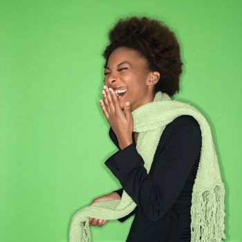 Pretty woman wearing green scarf laughing against green background.
