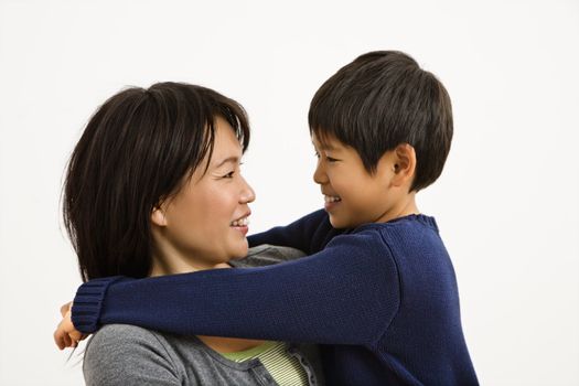 Asian mother and son hugging and smiling.