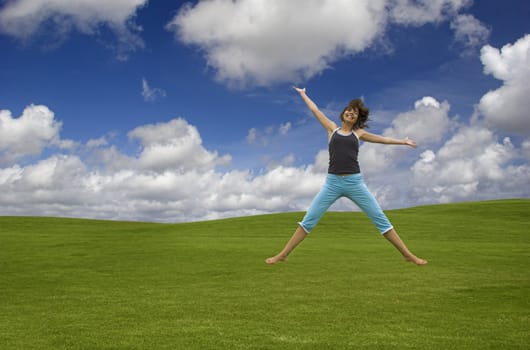 Beautiful happy woman jumping on a green field