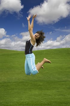 Beautiful happy woman jumping on a green field