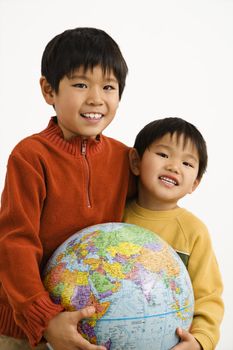 Two Asian boys holding world globe and smiling.