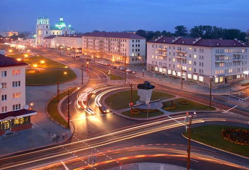 City centre at the night, the brisk movement of cars. On a background a cathedral church of Grodno