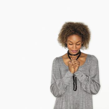 Woman with hands clasped together in prayer and eyes closed.
