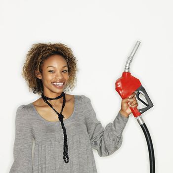 Portrait of pretty young woman smiling holding gas pump nozzle on white background.