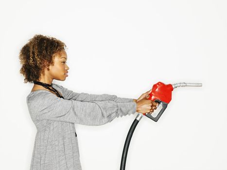 Portrait of pretty young woman holding gas pump nozzle like a gun on white background.
