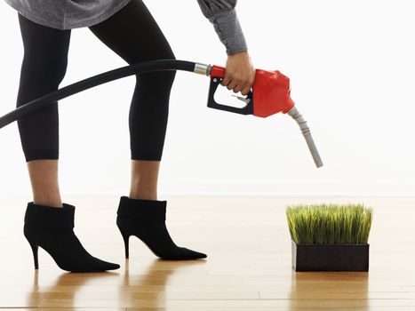 Woman holding gasoline pump nozzle over green grass.