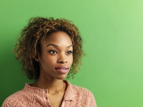 Head and shoulder portrait of young woman on green background.