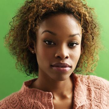 Close up portrait of pretty young woman against green background.