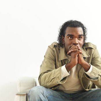 Portrait of man sitting with hands clasped as if in thought.