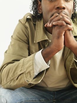 Portrait of man sitting with hands clasped as if in thought.