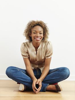 Portrait of woman sitting on wood floor smiling.