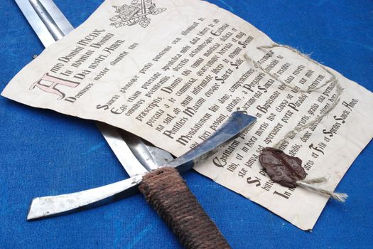 The ancient indulgence and the sword laying on a dark blue canvas