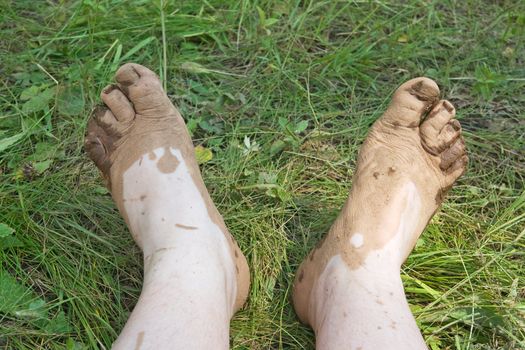 Two muddy feet on green grass