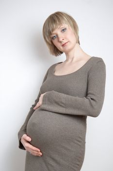 full-body portrait of a pregnant woman in a dark beige dress