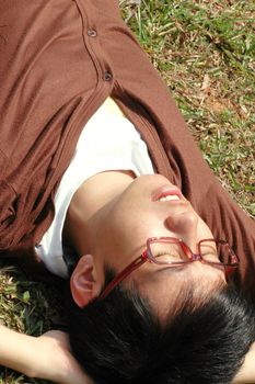 Young Chinese male lying on a field of grass