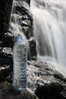 A bottle of fresh mineral water stands in waterfalls