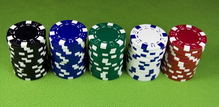 Five color poker casino stacks over green table