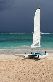A small tropical catamaran, sitting on the beach.