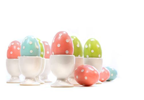 Polka dot easter eggs in cups on white background