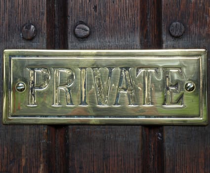 Private label on golden plate over a wooden door