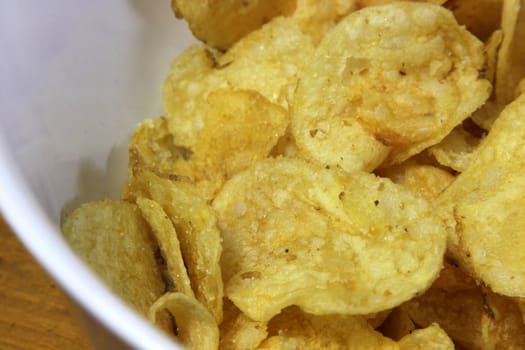 A close-up of a bowl of greasy potato chips.
