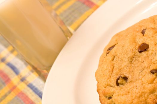 chocolate chip cookies on a white plate in front of a glass of milk