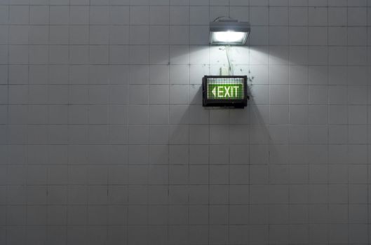 A grungy subway exit sign on a tiled wall
