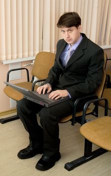 The person in a suit with the laptop in a lap