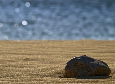 Stones laying on the sand on a beach in the Med